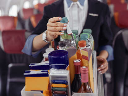 Female flight attendant providing service to passengers in airplane cabin