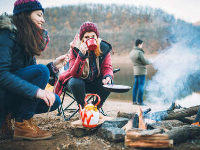 group of campers preparing food around a campfire in winter