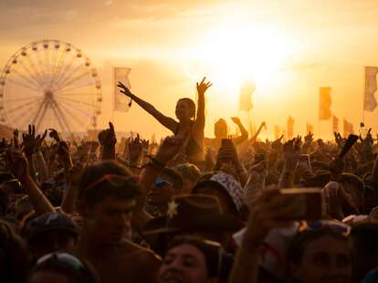 General view of the huge crowds enjoying the music at a music festival during a sunny day. 