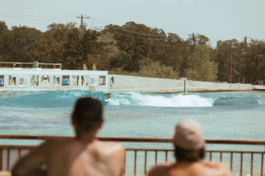 two men watching a surfer 