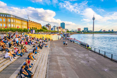 crowds of people sitting along the riverside promenade in dusseldorf