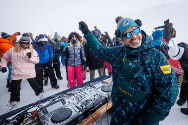 a DJ in snow gear playing for dancers