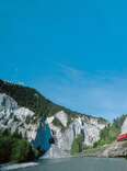 glacier express train, rolling by blue alpine lake, in switzerland