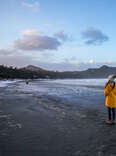 A woman standing on the coast of Vancouver Island looking at mountains.